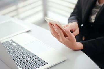 Person holding Mobile device over a laptop