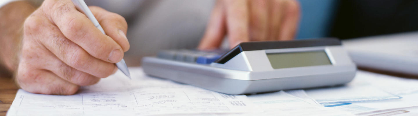 closeup of hands holding a pencil and using a calculator