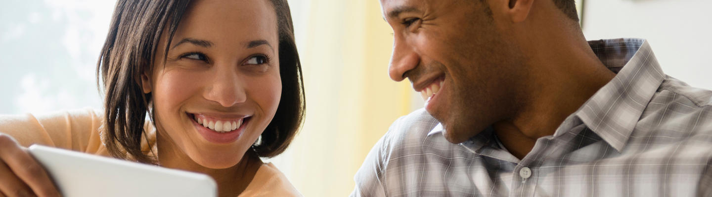 couple smiling at each other using a smart phone