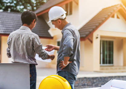 Man and contractor looking at blueprints and home